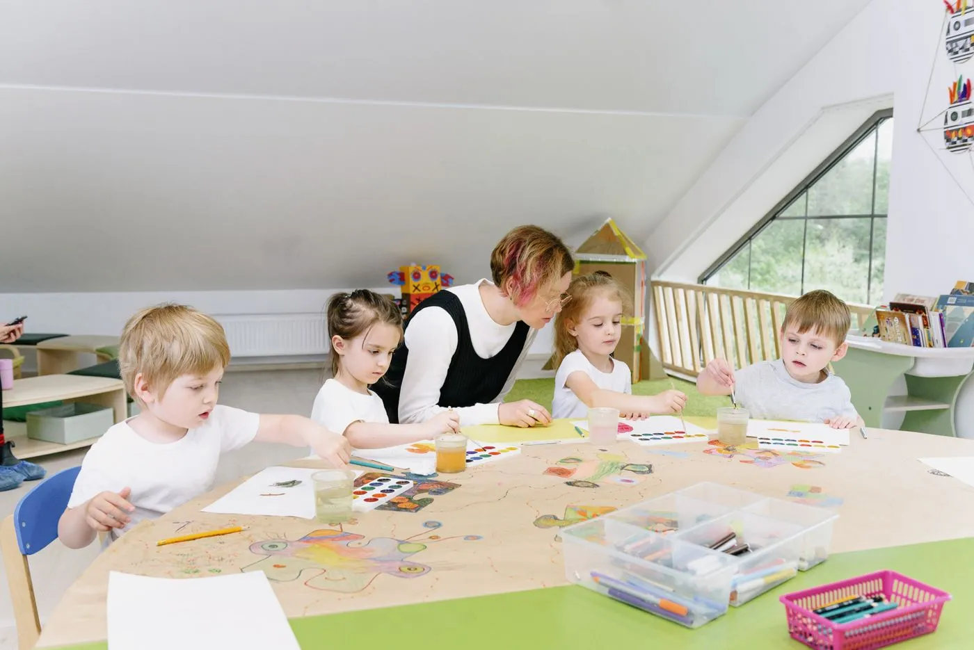 Professora e crianças em atividade na mesa do Infantil (imagem ilustrativa)